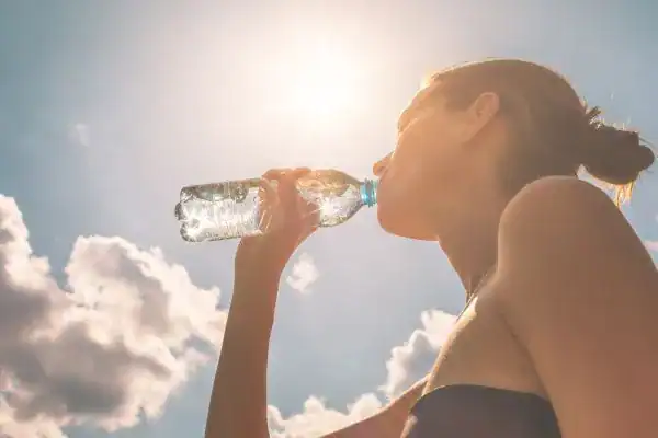 Hydration: The Secret Ingredient for a Toned Stomach and Enhanced Fitness 3 Image of woman drinking water to hydrate Hertford after run.