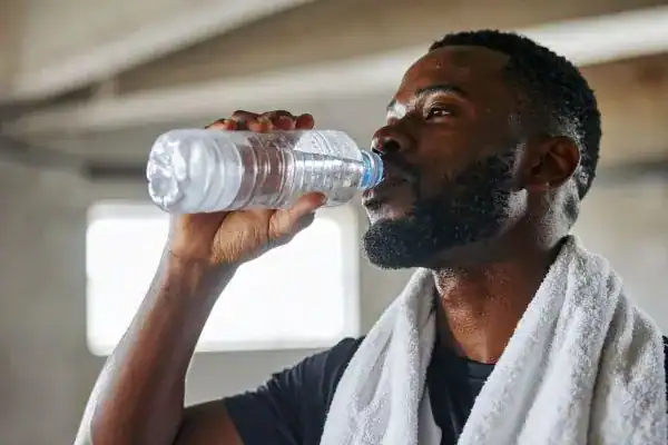 Image of man drinking water to improve hydration Hertford after work out.